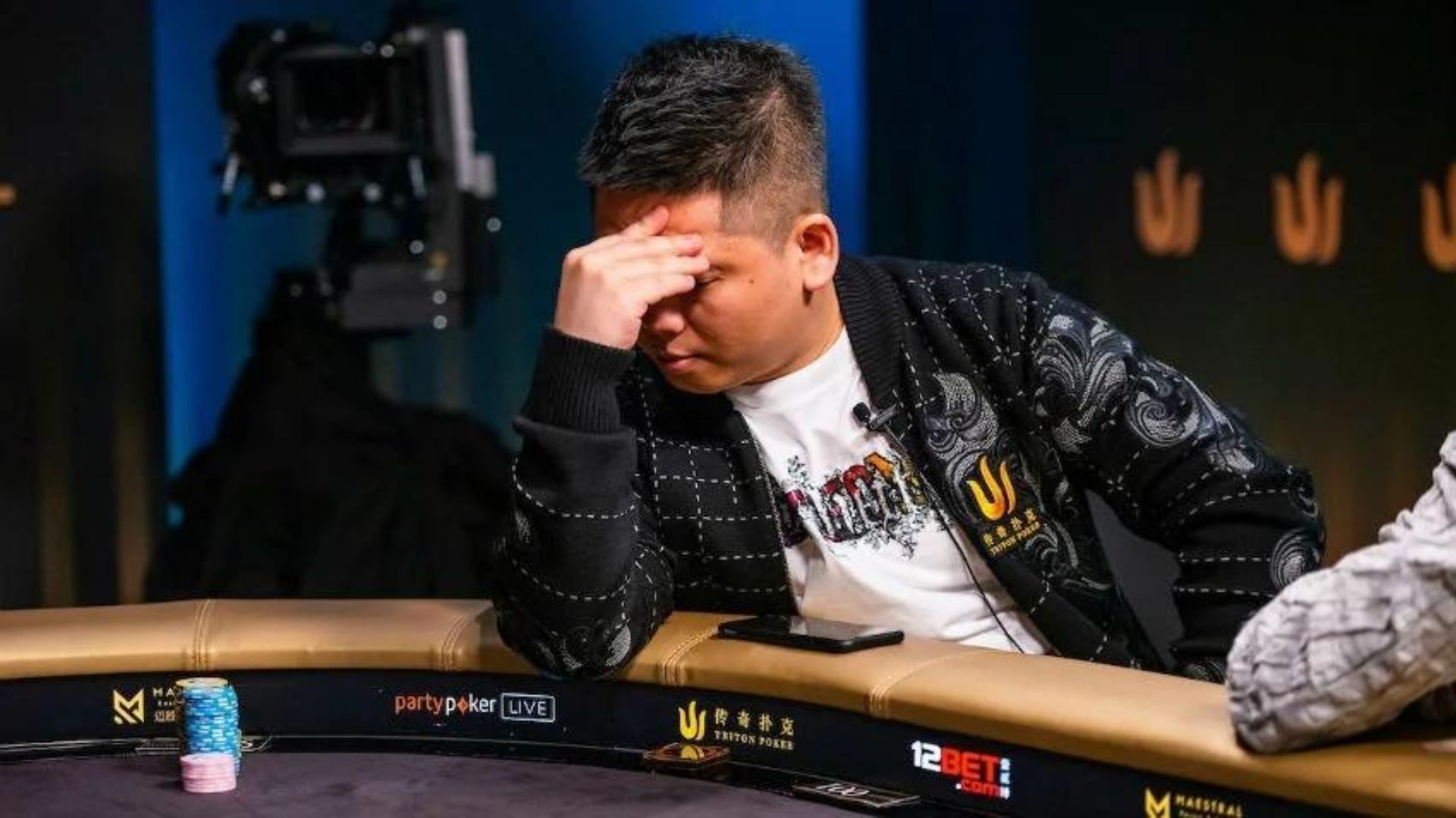 A Man wearing a Black jacket playing poker